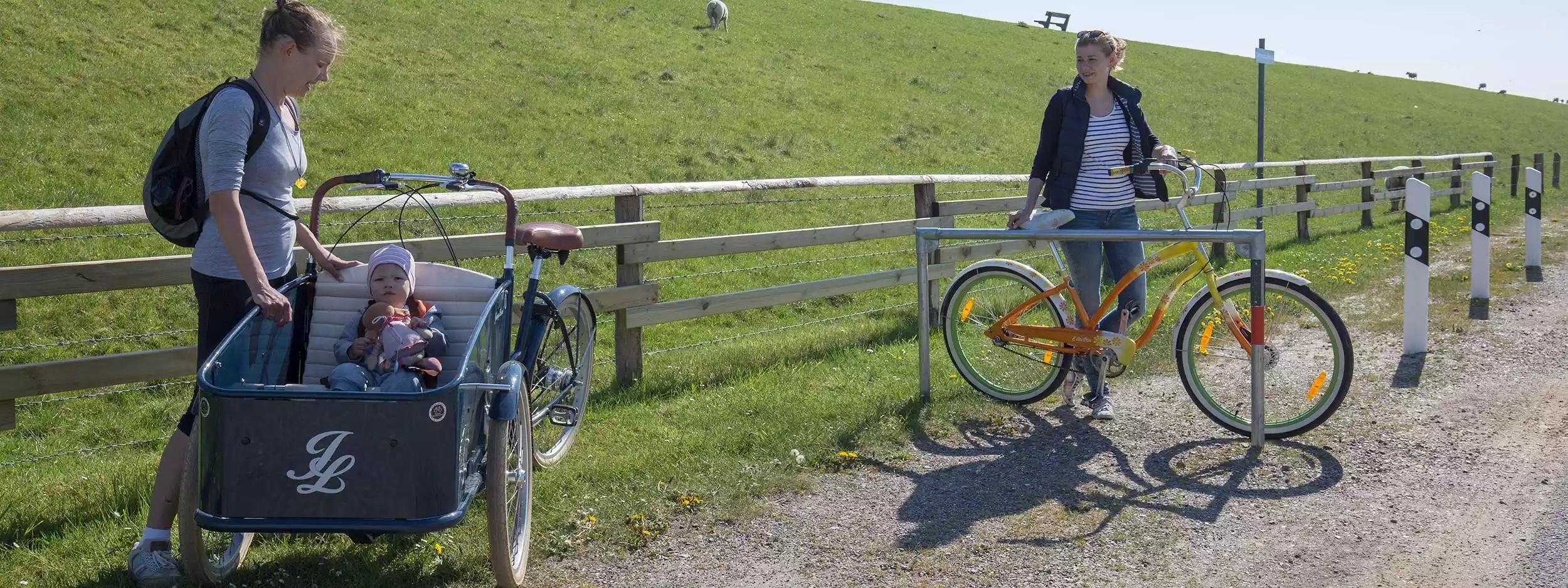 Zwei Frauen mit Lastenrad und Kind am Deichweg