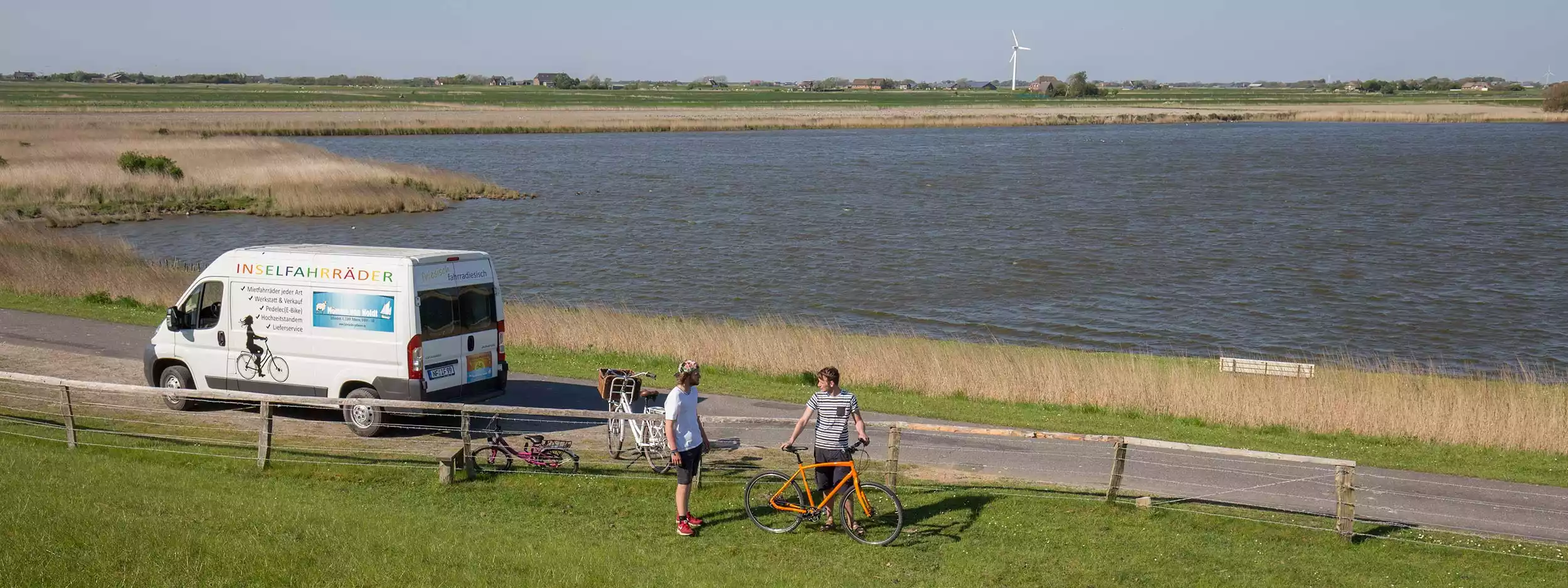 Inselfahrräder-Transporter mit Radfahrern am Wasser